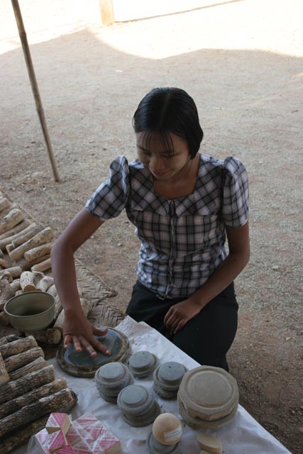 ,All women are whitenig their faces with such kind of local parfume made from ground bark of thanakha tree. Old Bagan market. Myanmar (Burma).